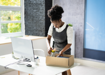 African American woman packing box at desk