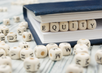 Dice spelling 'equity' resting in a book