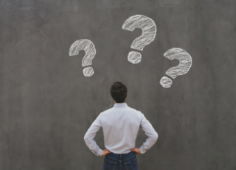 Man looking at chalkboard with 3 question marks on it